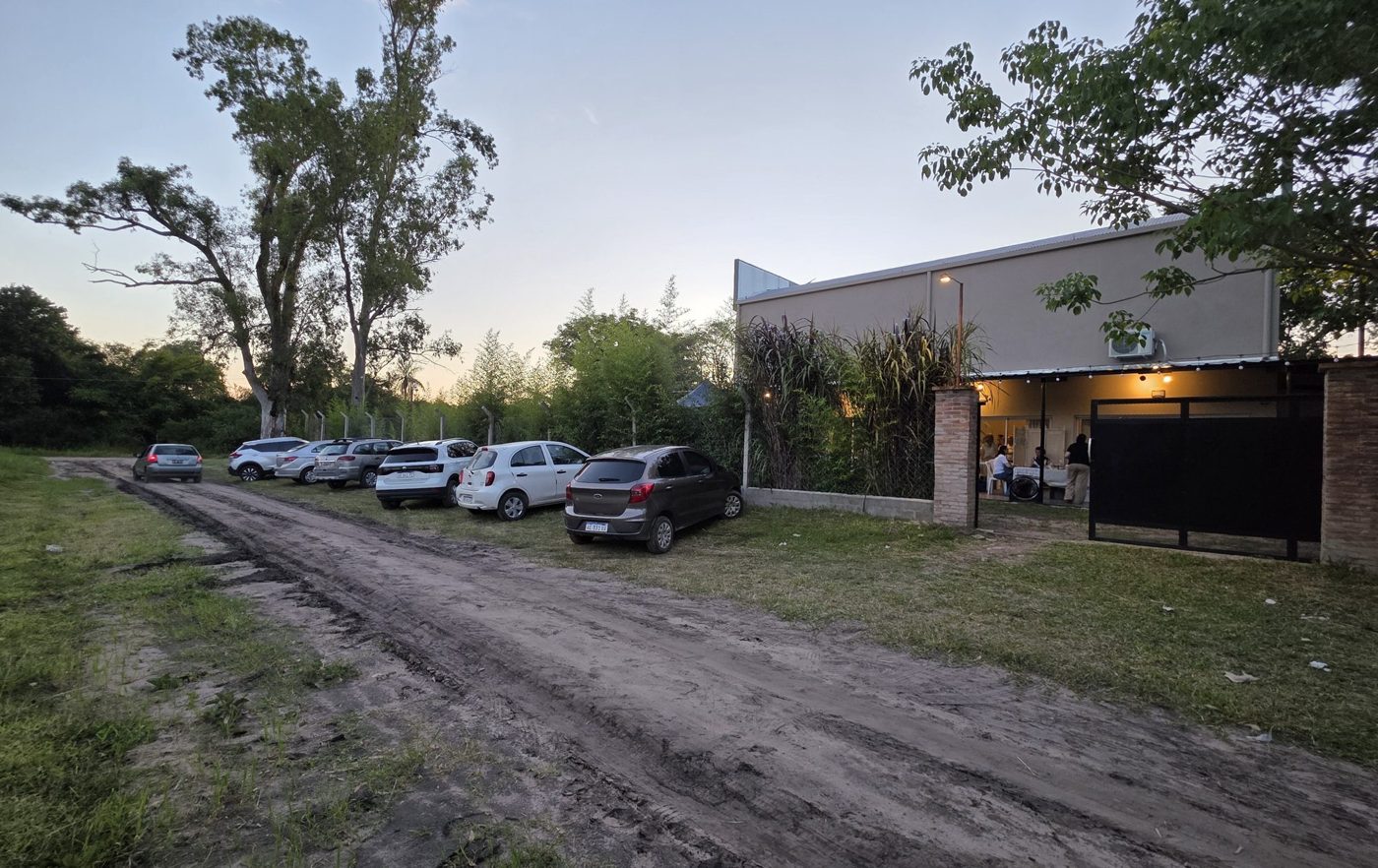 Acceso de tierra con autos estacionados junto al salón